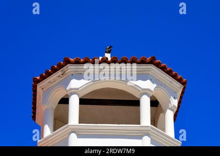 Kapuzenkrähe auf einem Kirchenturm vor blauem Himmel, Griechenland. Stockfoto