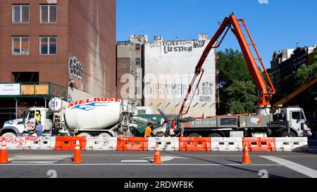 Ein Betonpumpenwagen und ein Betonmischwagen auf einer Baustelle in New York City. Der Pumpenwagen hat einen ausfahrbaren Ausleger für die Reichweite. Stockfoto