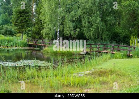 Zwei kleine Holzbrücken zwischen kleinen Teichen in einem gepflegten wunderschönen Park. Stockfoto
