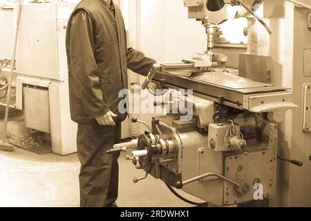 Ein männlicher Arbeiter arbeitet an einer größeren Metallschleusen-Drehmaschine, Ausrüstung für Reparaturen, Metallarbeiten in einer Werkstatt in einer Metallurgieanlage in einem Reparaturprogramm Stockfoto