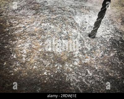 Ein robuster Hartmetallbohrer bohrt ein Loch in einen großen grauen Stein. Ansicht schließen. Der Hintergrund. Stockfoto