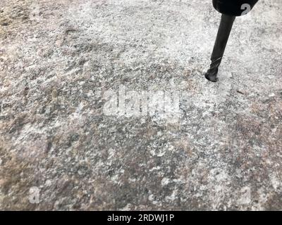 Ein robuster Hartmetallbohrer bohrt ein Loch in einen großen grauen Stein. Ansicht schließen. Der Hintergrund. Stockfoto