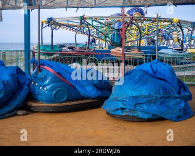 Verlassener Luna Park. Autodrom. Die Autos sind mit Planen bedeckt. Alte Karussells. Funktioniert nicht. Kaputte Anziehung. Resort im Winter. Kaputtes Geschäft. E Stockfoto