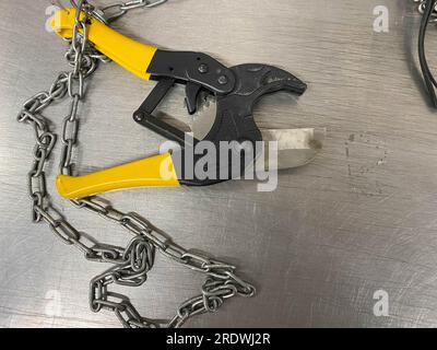 Große, scharfe Metallscheren, Metallschneider mit Ketten, liegen auf einem Eisentisch. Handwerkzeuge für Schlosser. Der Hintergrund. Stockfoto