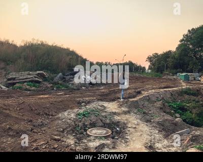 Baustelle. Gefährliche Baustellen. Ein Mädchen mit langen dunklen Haaren läuft auf einer Baustelle durch Sand und Schlamm. Gefährlicher Gang durch Stockfoto