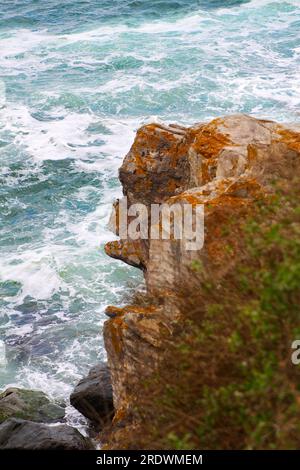 Seitlicher Blick auf den braunen Teil des Felsens in Form eines Affen vor dem Hintergrund eines rauen blauen Meeres mit großen Wellen, die auf den Felsen brechen Stockfoto