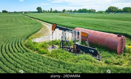 Ölpumpenwagenheber aus der Luft in der Mitte des Feldes mit Tank und Wartungsstraße Stockfoto