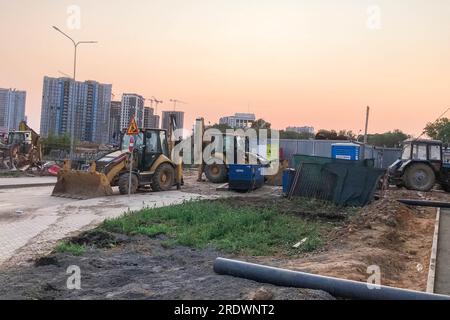 Baustelle. Baumaschinen in leuchtenden Farben stehen auf der Baustelle neben der Baustelle. Bagger, Baukräne für Bauzwecke Stockfoto