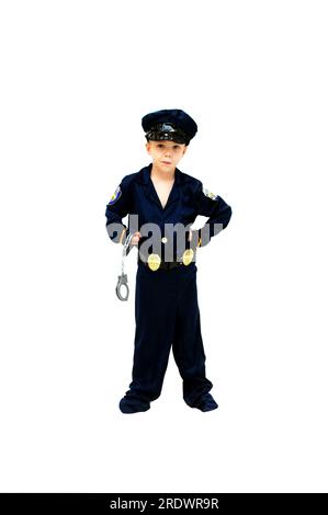 Der kleine Junge, der als Polizist verkleidet ist, ist bereit, jede Verhaftung vorzunehmen. Er hat eine Grimasse im Gesicht und hält seine Handschellen. Stockfoto