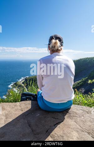 Eine unbekannte Frau, die im Sommer die Aussicht auf die Berge genießt. Glücklicher Wanderer genießt die Aussicht Stockfoto