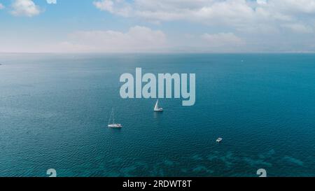 Luftdrohne, ultrabreites Panoramafoto eines wunderschönen Segelboots mit weißen Segelsegeln, das tiefblaues Meer in der Nähe des Zielhafens im Mittelmeer bereist Stockfoto