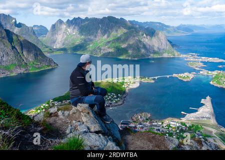 Entspannte, glückliche Wanderer genießen die atemberaubende Aussicht auf den Reinebringen-Gipfeln der Lofoten-Inseln, Fjorde, Norwegen Stockfoto