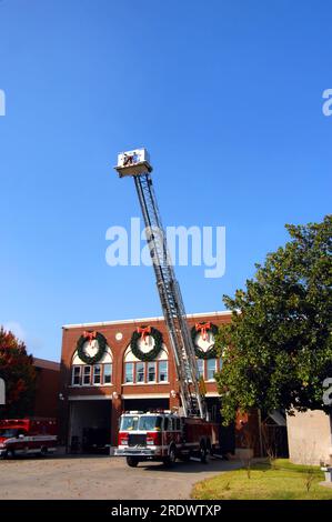 Die Leiter ist auf dem Feuerwehrwagen, der Reparaturen durchführt, verlängert. Die Feuerwehr bereitet sich darauf vor, Weihnachtsdekorationen in der Stadt zu installieren. Stockfoto