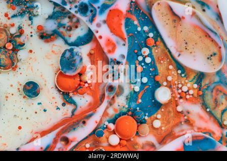 Weiße Milch mit abstrakten Perlen weißer orangefarbener und blauer Blasen im Hintergrund Stockfoto