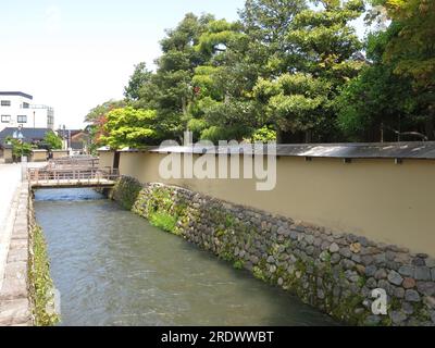 Der Nagamachi Samurai-Bezirk in Kanazawa zeichnet sich durch Wasserkanäle entlang der verwinkelten Straßen, gelben Erdmauern und historischen Residenzen aus. Stockfoto