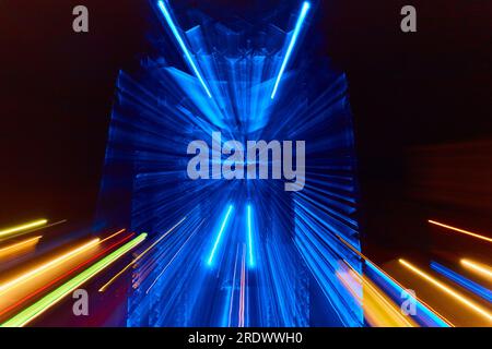 Verschwommene Nachtaufnahme von blauen Neonlichtern mit verschwommener gelber und roter Stadt mit Neongrün-Blitz Stockfoto