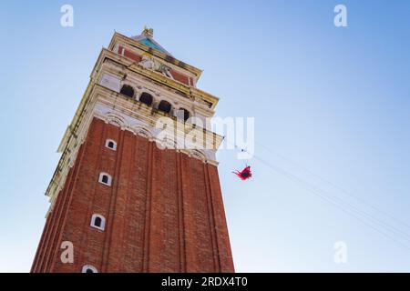 The Flight of the Angel“-Frau, gekleidet mit Engelsflügeln, die an ein Seil gebunden sind, das vom Campanile des Markusplatzes hinuntergeht, verkündete sie den Beginn des berühmten Karnevals Stockfoto