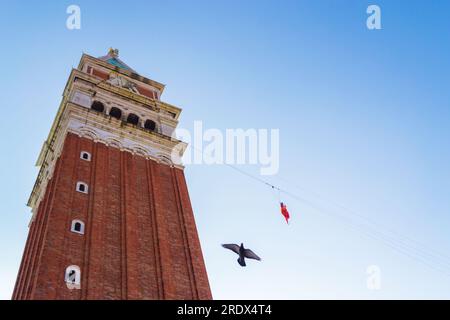 The Flight of the Angel“-Frau, gekleidet mit Engelsflügeln, die an ein Seil gebunden sind, das vom Campanile des Markusplatzes hinuntergeht, verkündete sie den Beginn des berühmten Karnevals Stockfoto