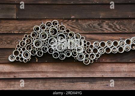 Abstrakte Kunst aus weißen PVC-Rohren auf prächtigen dunkelbraunen Holzverkleidungen Stockfoto