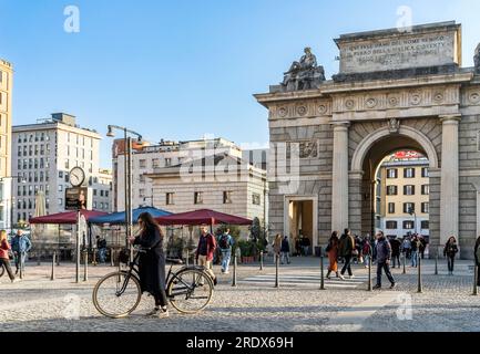Piazza XXV Aprile with people walking and a cyclist. In the background, Porta Garibaldi gate. Milan city center, Lombardy region, Italy Stock Photo