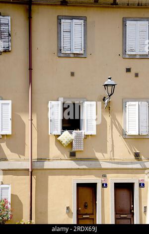 Fassade eines Wohngebäudes in der „Rena Vecia“, dem alten Viertel von Triest, mit offenen Fenstern und malerischen Hängekissen, Triest, Italien Stockfoto