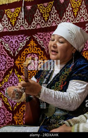 Kasachstan, Hunnen-Ethno-Dorf. Eine Kasacherin, die in einem Jurten die Dombra spielt. Stockfoto