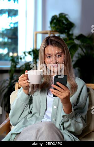 Frau, die zu Hause ein Smartphone mit Gesichtserkennungssystem verwendet. Sicherheitsanwendung, die ihr Gesicht scannt, um die Identität des Besitzers zu bestätigen Stockfoto