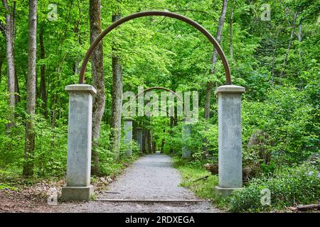 Eine Reihe weißer Steinsäulen, Metallbögen, Rose Island, Rosengang, Pfad durch den Wald Stockfoto