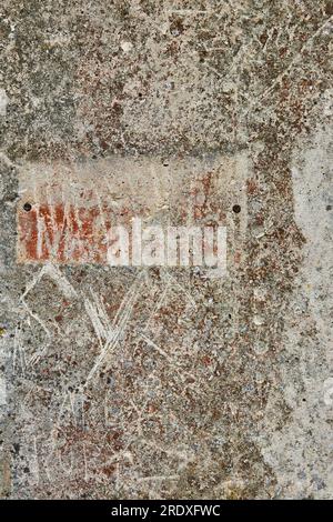Zerkratzte Betonwand mit Rost- und Schmutzflecken korrodiert und markiert Stockfoto
