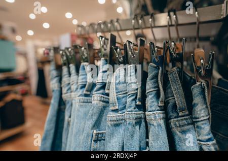 Denimhosen im Bekleidungsgeschäft. Jeans an Kleiderbügel hängen im Kleiderladen. Modegeschäft im Einkaufszentrum. Kleidung an Kleiderbügeln Stockfoto