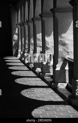 Ein Schwarzweißbild einer langen Linie von Bögen, die satte Kontraste und dunkle Schatten erzeugen. Stockfoto