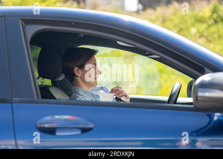 Frau fährt Auto mit defekter Klimaanlage und leidet an heißen Sommertagen an Hitze. Stockfoto