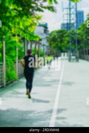 Vertikales unscharfes Bild von Personen, die auf dem Skywalk joggen, der Lumphini Park und Benchasiri Park miteinander verbindet, natürliches Licht. Stockfoto