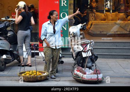 Frau ruht sich aus, bringt Essen zum Verkauf in zwei Körben, die an einem Stab auf der Schulter hängen. saigon, 2014, asien, asien, zeigt Richtung, zeigt Richtung, Unterricht, Unterweisung Stockfoto