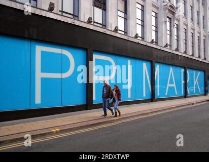 Das Äußere des Primark Stores oder Shops, Manchester, Großbritannien, zeigt den Namen des Primark in großen Buchstaben; ein Mann, der eine Frau vorbeigeht, ein Kopierfeld Stockfoto