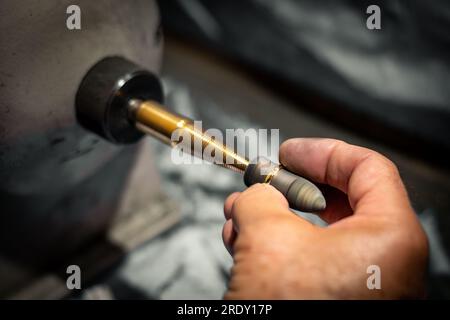 Ein Goldschmied poliert in seiner Schmuckwerkstatt einen Goldring. Juwelierhände arbeiten in seinem Kunsthandwerksstudio. Stockfoto