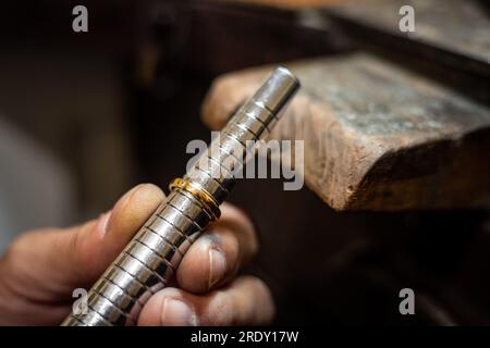 Juwelierhände messen und prüfen den Dorn der Ringgrößenlehre. Goldschmied, der in seiner Schmuckwerkstatt einen Goldschmuck repariert. Stockfoto