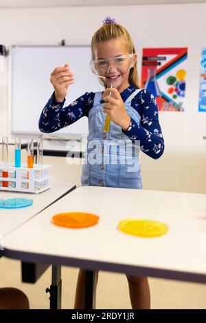 Porträt eines glücklichen weissen Schulmädchens mit Schutzbrille, das im Labor experimentiert Stockfoto