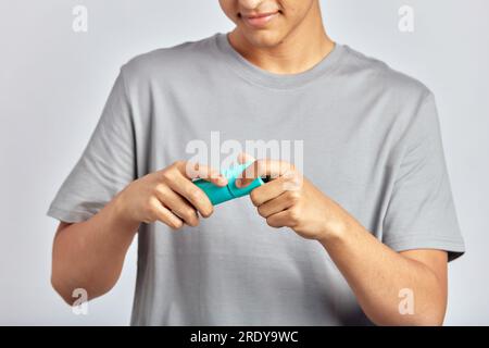 Ein fröhlicher lächelnder Typ, der eine Gesichtsspülflasche öffnet und sich darauf vorbereitet, das Schönheitsprodukt auf sein Gesicht aufzutragen. Der junge Mann benutzt einen feuchtigkeitsspendenden Hautreiniger in seinem Skincar Stockfoto