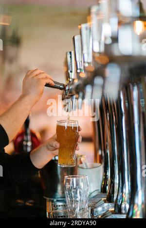 Hände des Kellners, der Bier in Glas aus dem Wasserhahn an der Bar füllt Stockfoto