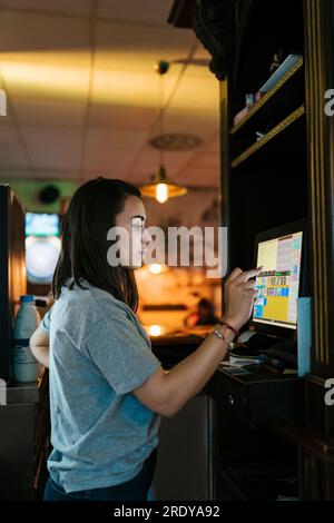 Junger Kassierer, der einen Touchscreen-Computer in der Bar bedient Stockfoto