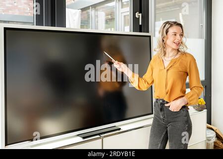 Blonde Geschäftsfrau, die ihre Präsentation über ein interaktives Whiteboard hält Stockfoto