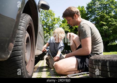 Vater und Sohn wechseln im Hof die Autoreifen Stockfoto