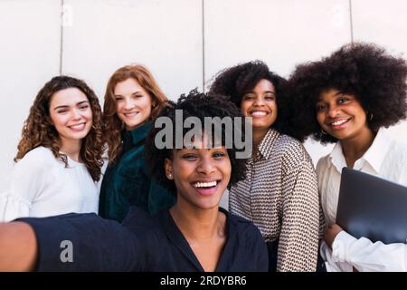 Glückliche Geschäftsfrau, die Selfie mit Kollegen macht Stockfoto