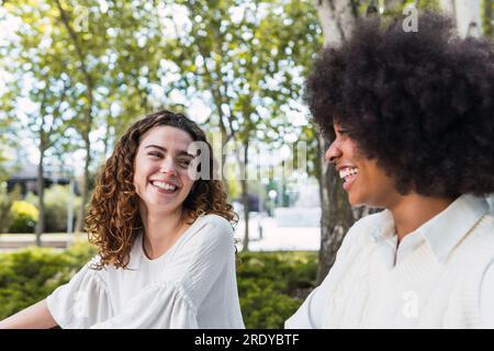 Lächelnde lockige Frau, die Zeit mit einem Freund verbringt Stockfoto