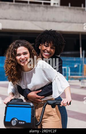 Glückliche junge Freunde, die an sonnigen Tagen mit dem Elektrofahrrad fahren Stockfoto