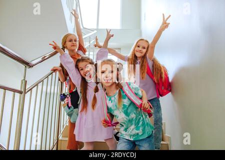 Lächelnde Schulmädchen mit erhobener Hand auf der Schultreppe Stockfoto