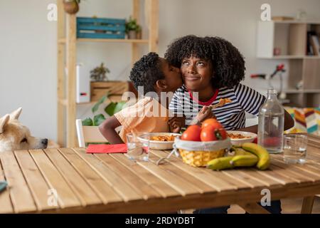 Ein Junge küsst Mutter auf die Wange und isst zu Hause zusammen Stockfoto