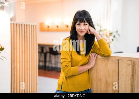 Lächelnde, reife Geschäftsfrau, die im Amt steht Stockfoto