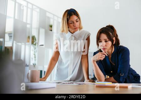 Kollegen, die im Kreativbüro am Schreibtisch ein Brainstorming über das Dokument durchführen Stockfoto